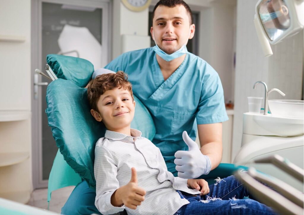 Smiling child sitting with a pediatric dentist after treatment, representing successful placement and follow-up care for a kids dental spacer.