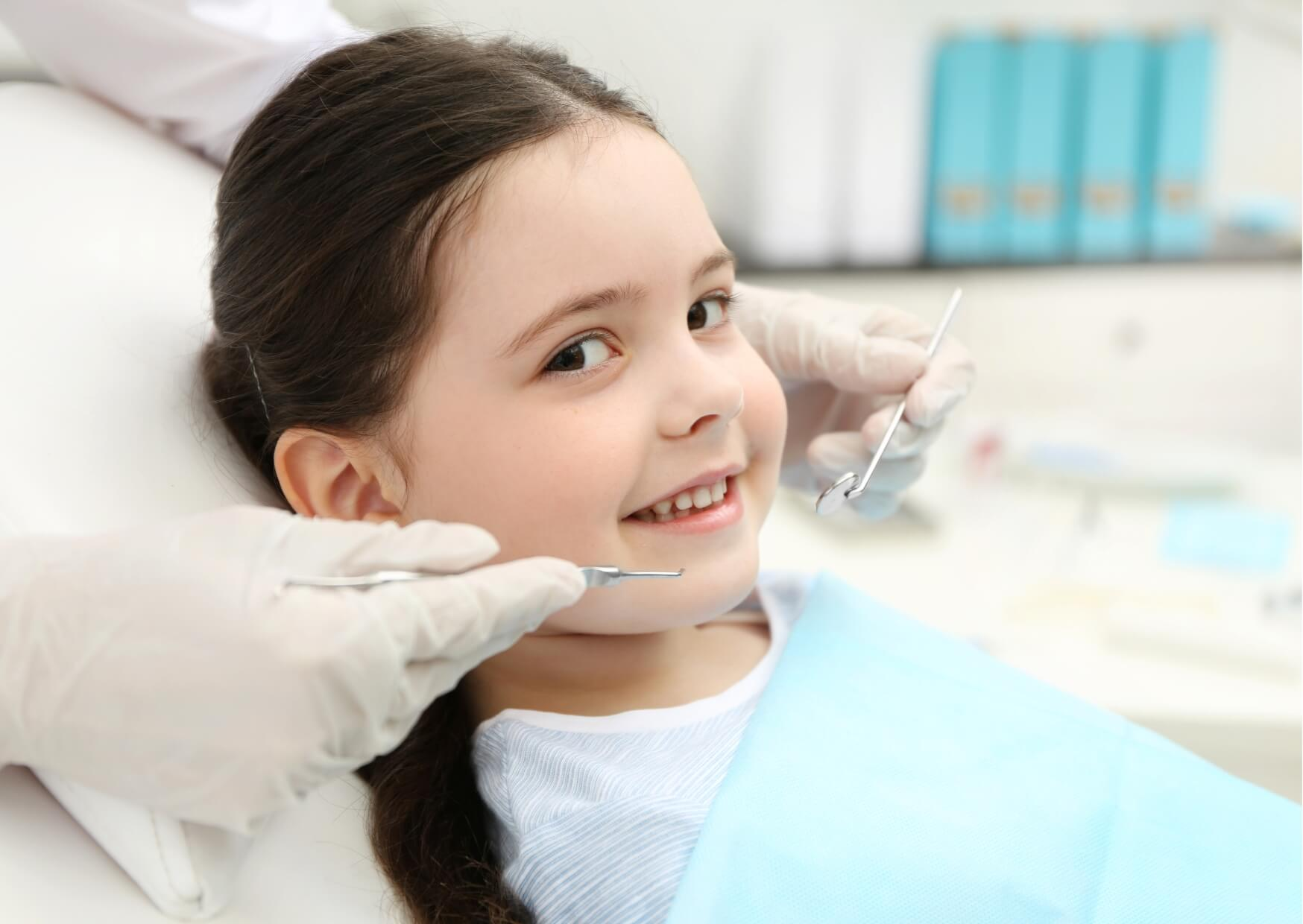 Young child receiving a dental examination, illustrating routine monitoring and evaluation for a pediatric dental spacer after early tooth loss.