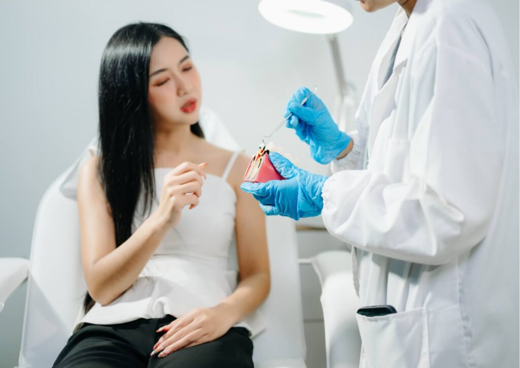 Dentist explaining treatment options for a chipped tooth using a tooth model during a patient consultation.