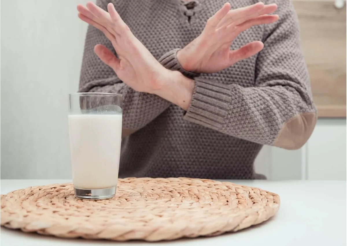 Person refusing a glass of milk, illustrating guidance on avoiding dairy after dental implant surgery.