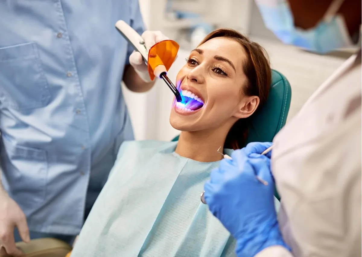 Dental professional curing dental sealants with a special light after application to a patient’s teeth.