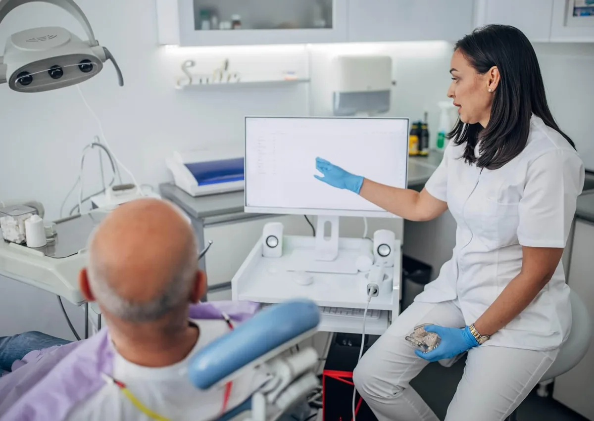 Dentist discussing full mouth dental implants cost and treatment options with a patient during a consultation.