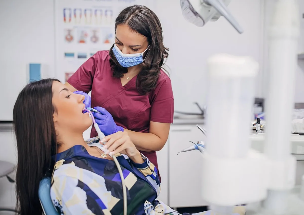 Dental hygienist removing plaque from a patient’s teeth during a professional dental cleaning.