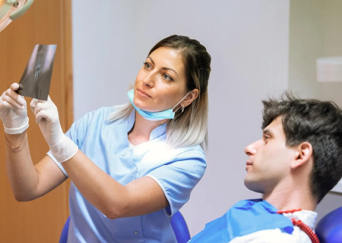 Dentist reviewing a dental X-ray with a patient during an evaluation for zygomatic dental implants.