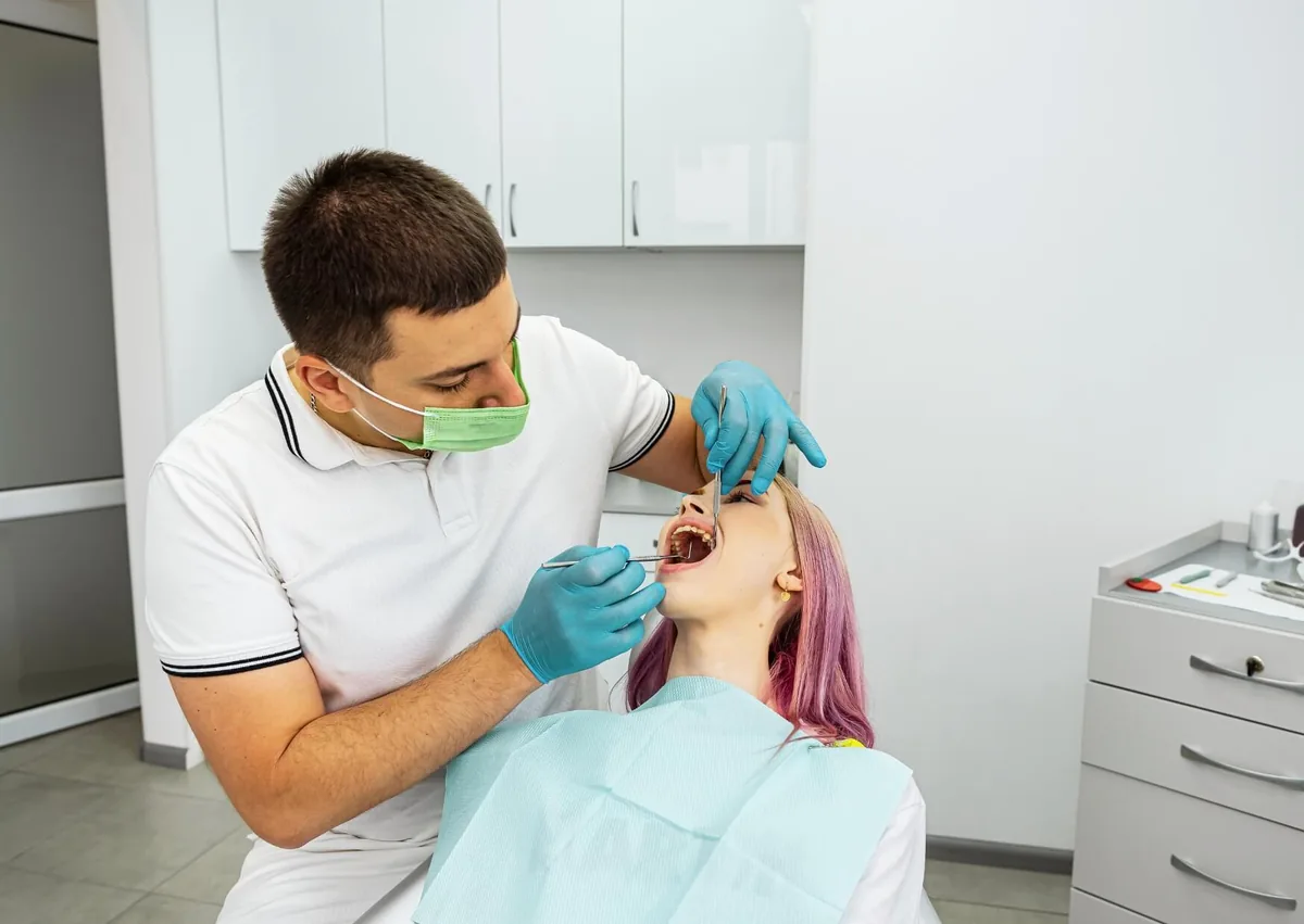 Dentist examining a patient's mouth for canker sores and other oral health concerns during a dental checkup.