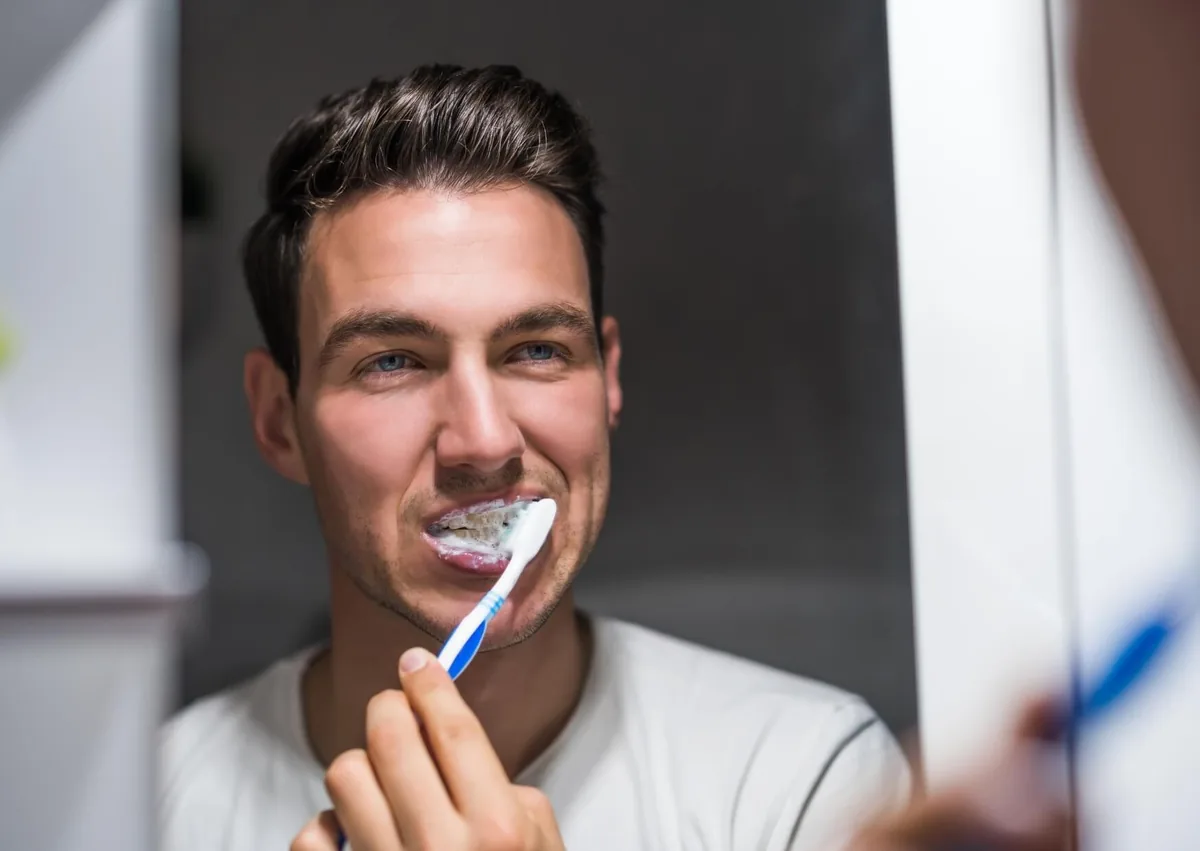 Man brushing his teeth with a toothbrush and toothpaste as part of a daily oral hygiene routine to prevent cavities.