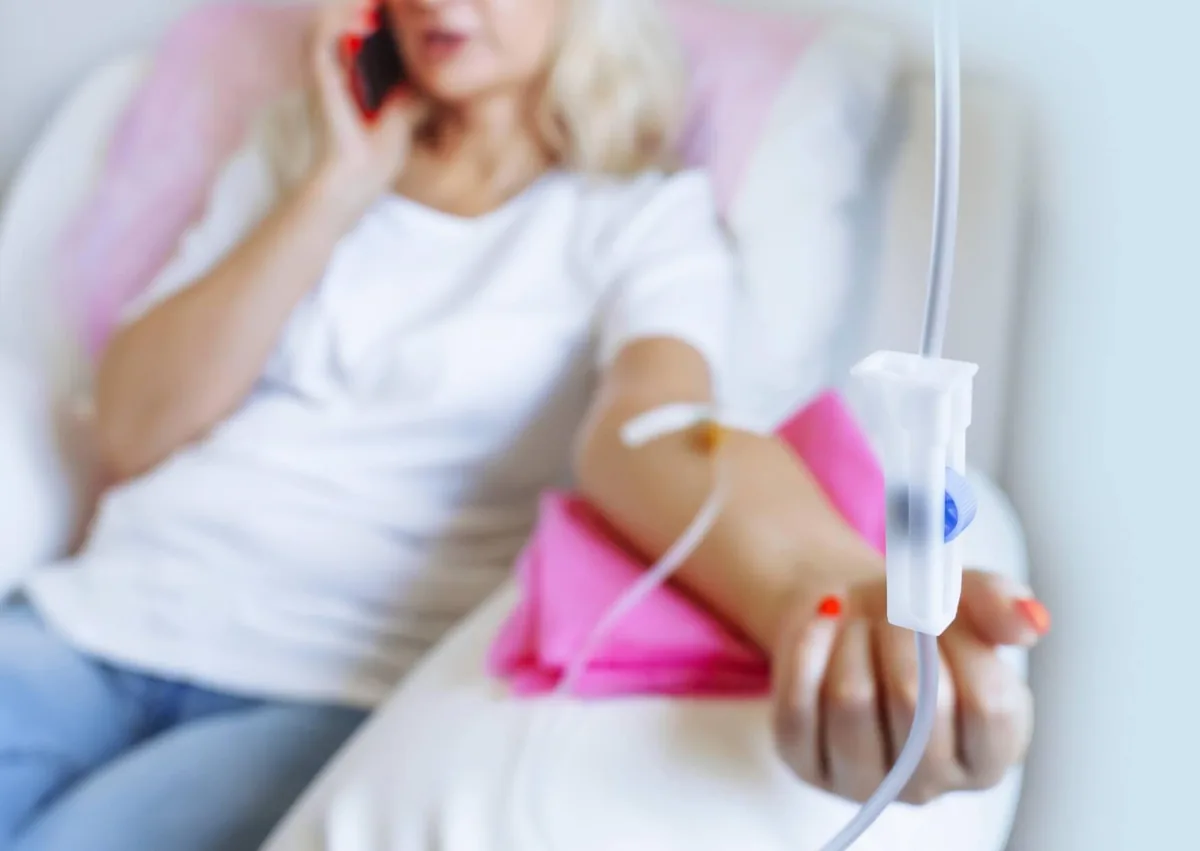Patient receiving intravenous medication through an IV line while reclining in a medical chair, illustrating IV dental sedation.